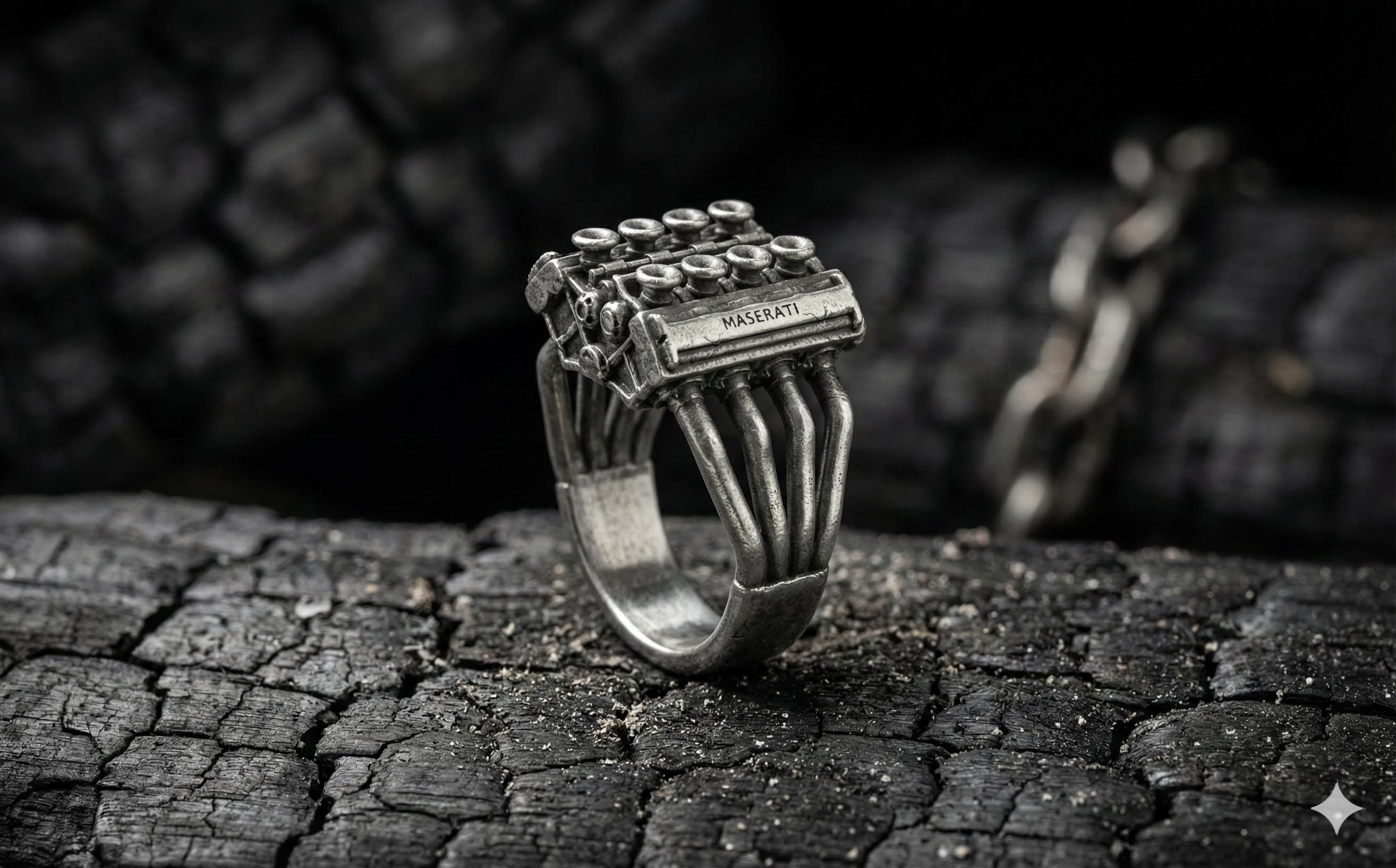 A silver ring with a unique design sits on a cracked, black surface.