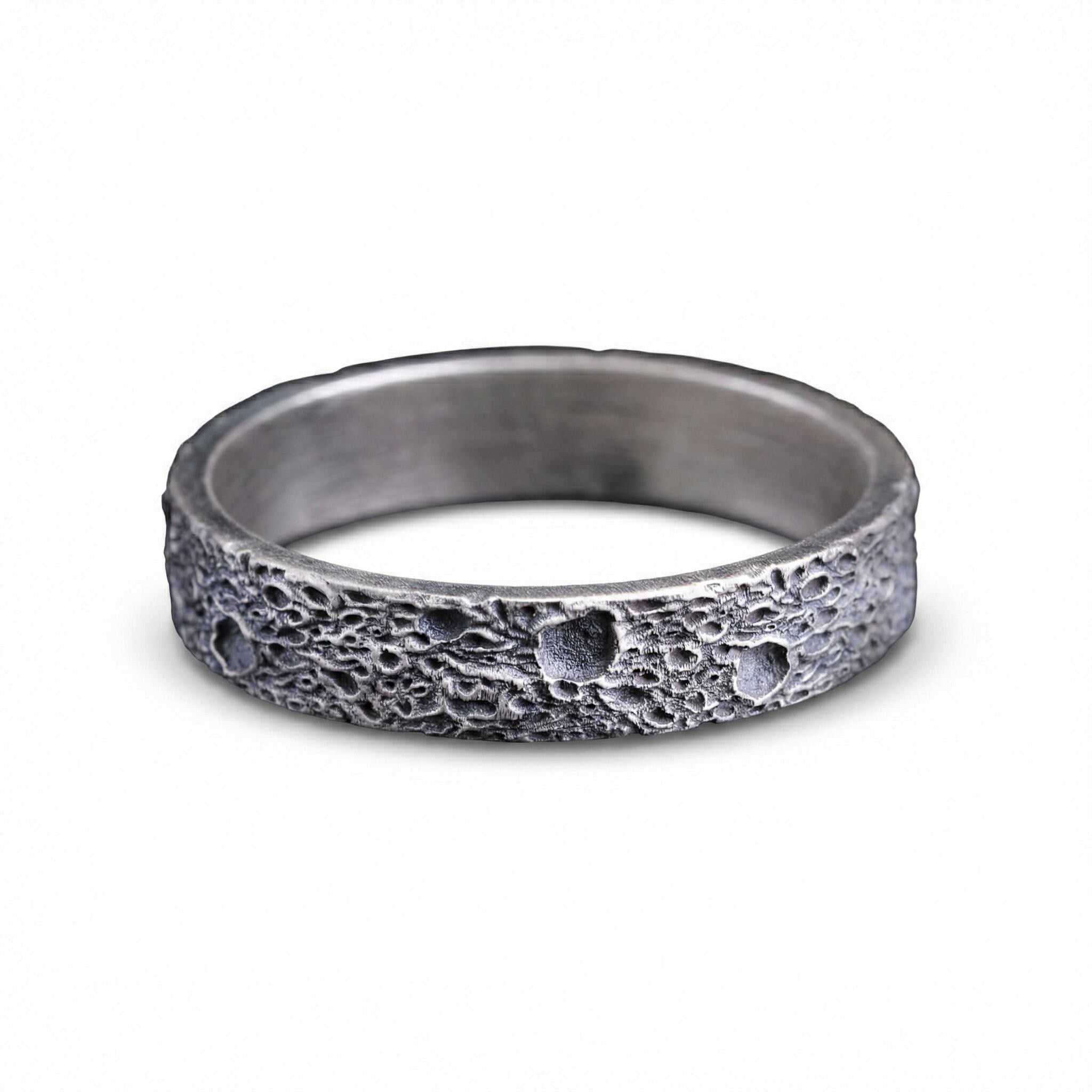 A silver ring with a textured surface resembling the moon.