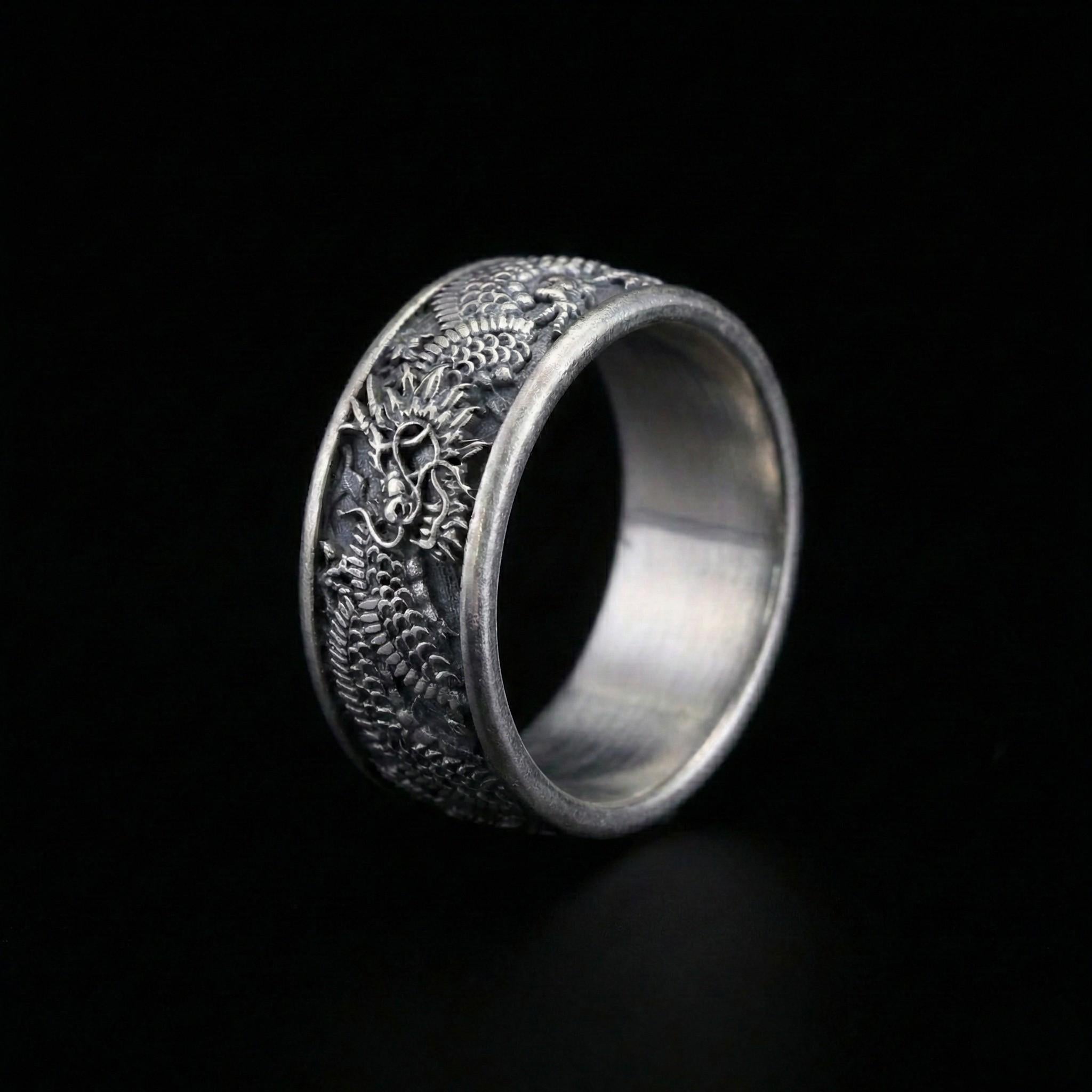 A silver ring with an intricate dragon design on the band.