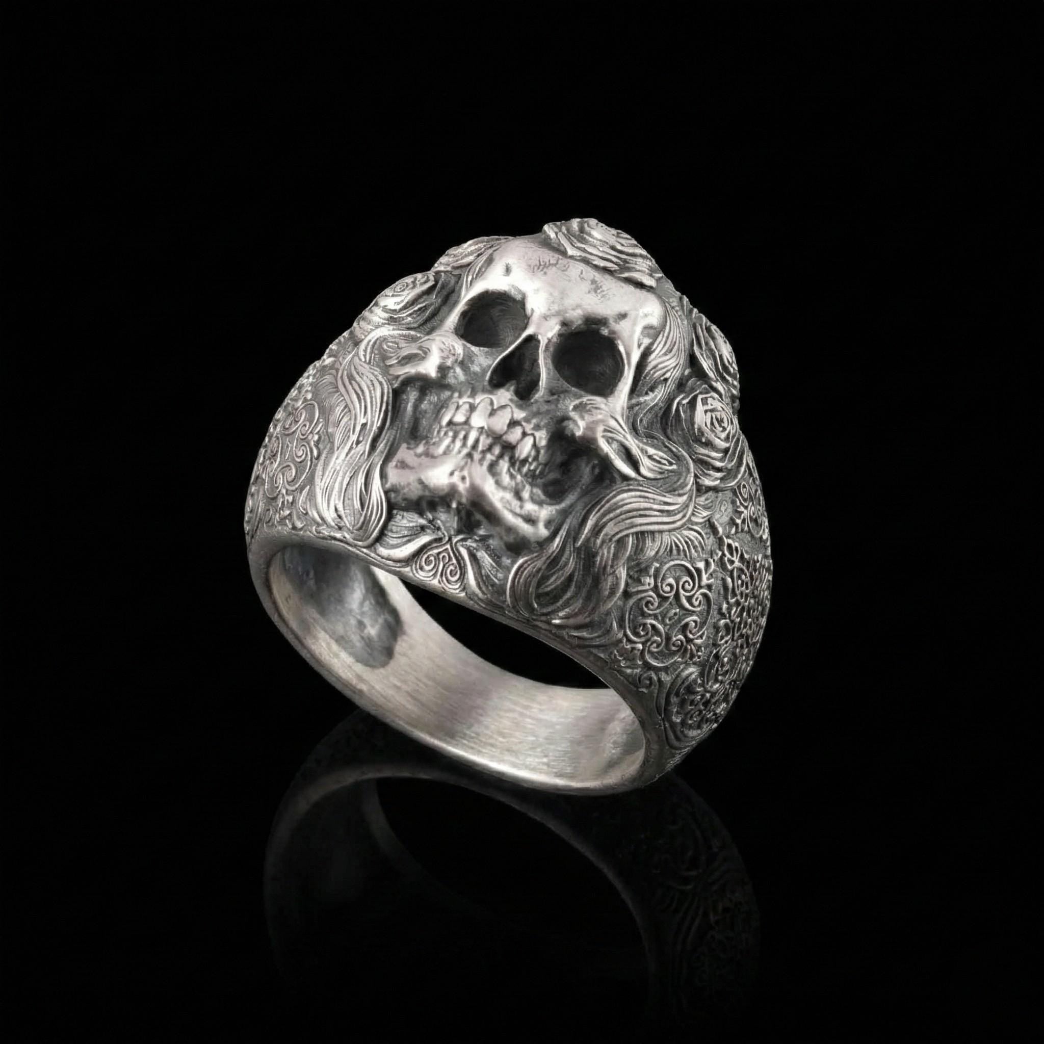 A silver ring with an intricate design featuring a skull and floral elements.