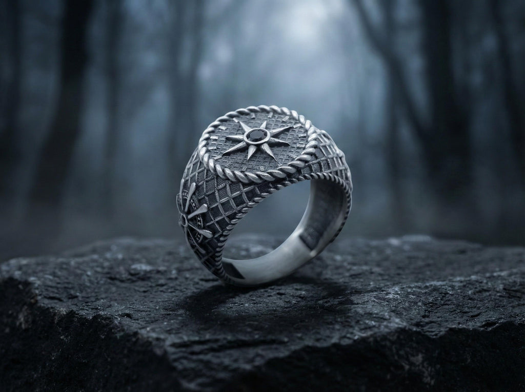 A silver ring with a star design sits on a rock in a dark, wooded area.