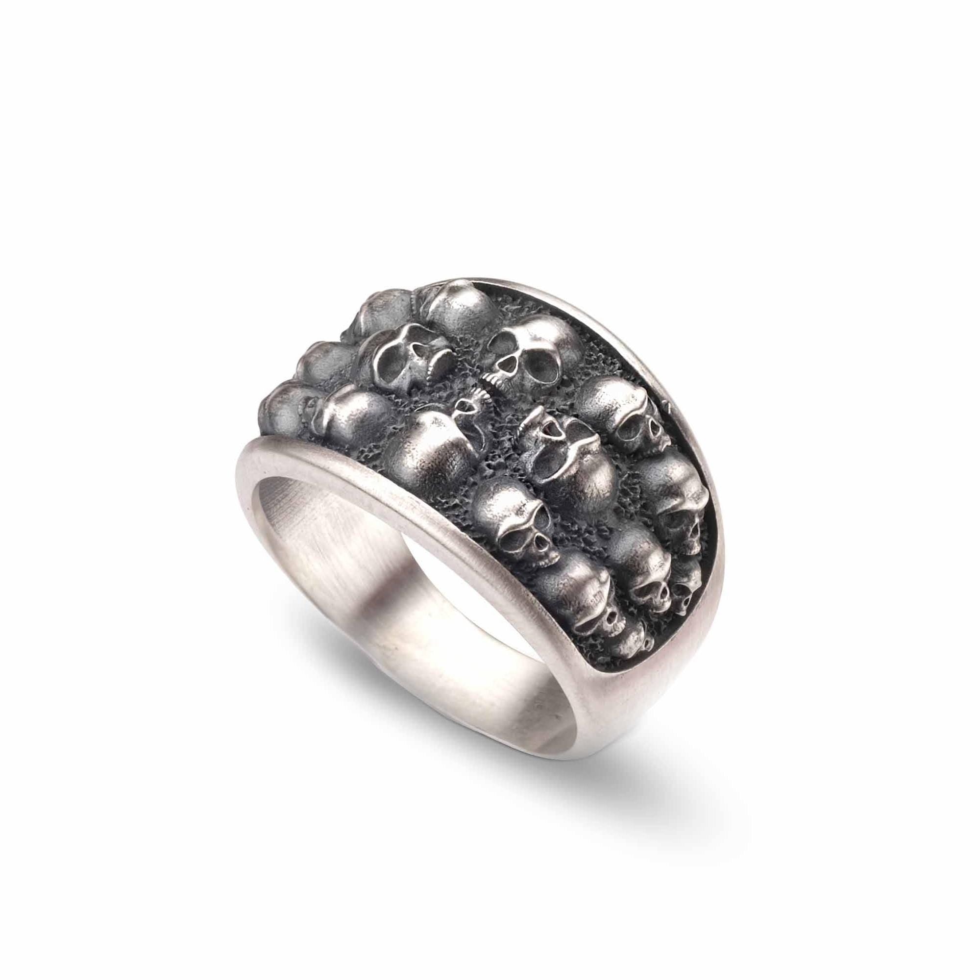 A silver ring with a unique design featuring a large number of skulls arranged in a circular pattern.