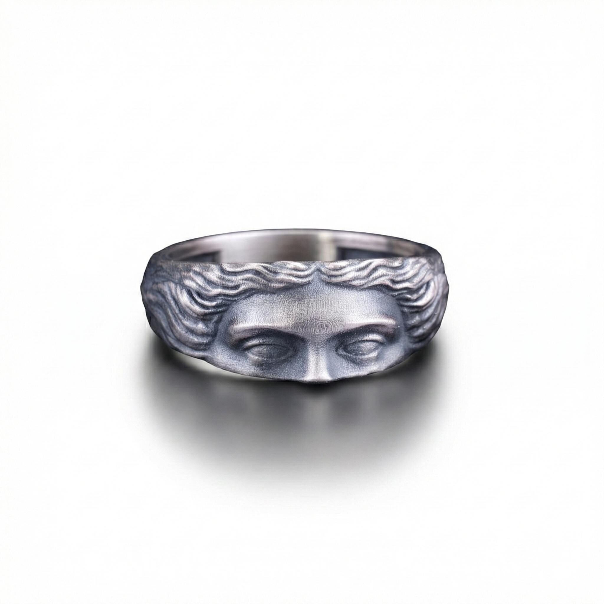 A silver ring with a face design on it.