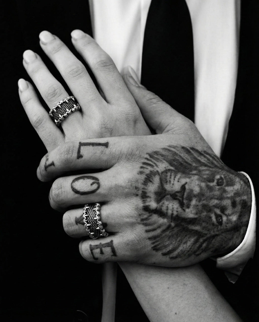 A close-up black and white image of a person's hands, with the word "LOVE" written on the fingers.