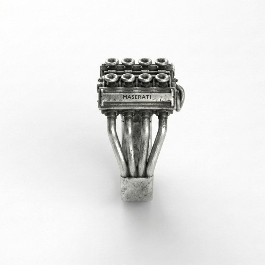 A silver ring with a detailed engine design, featuring multiple pipes and components.