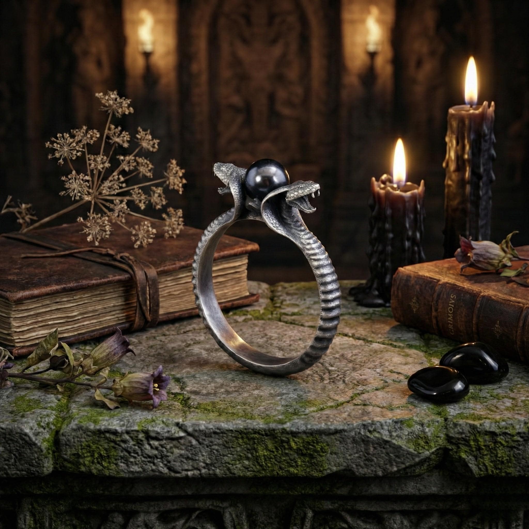a ring with a snake design, surrounded by candles, books, and flowers on a stone surface.
