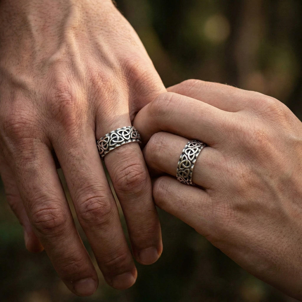A close-up image of two hands wearing silver rings, with the rings being intricately designed.