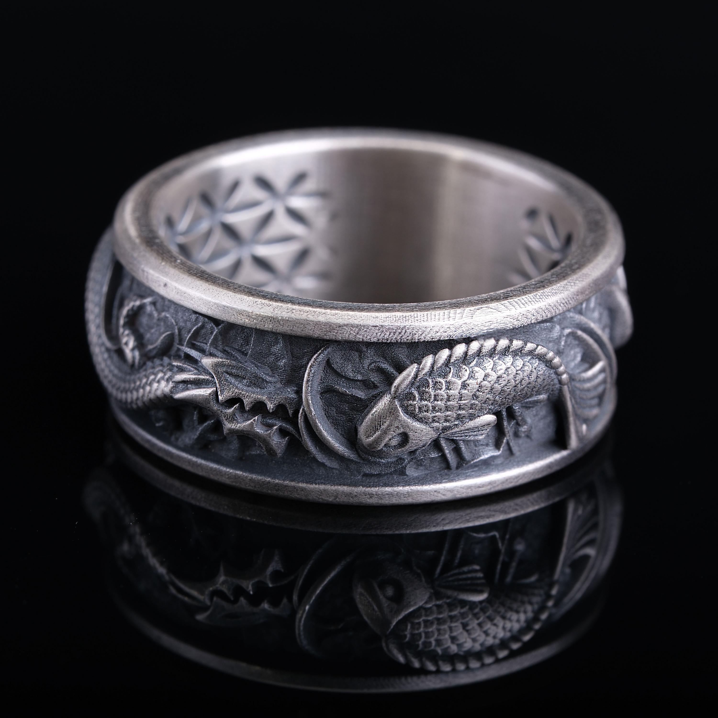 A silver ring with an intricate design featuring a dragon and a fish.
