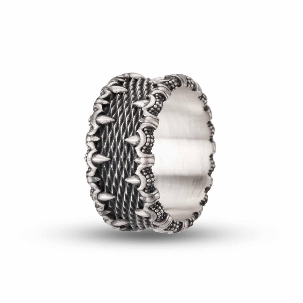 A silver ring with an intricate, textured design featuring spikes or spikes and dots along the edges.