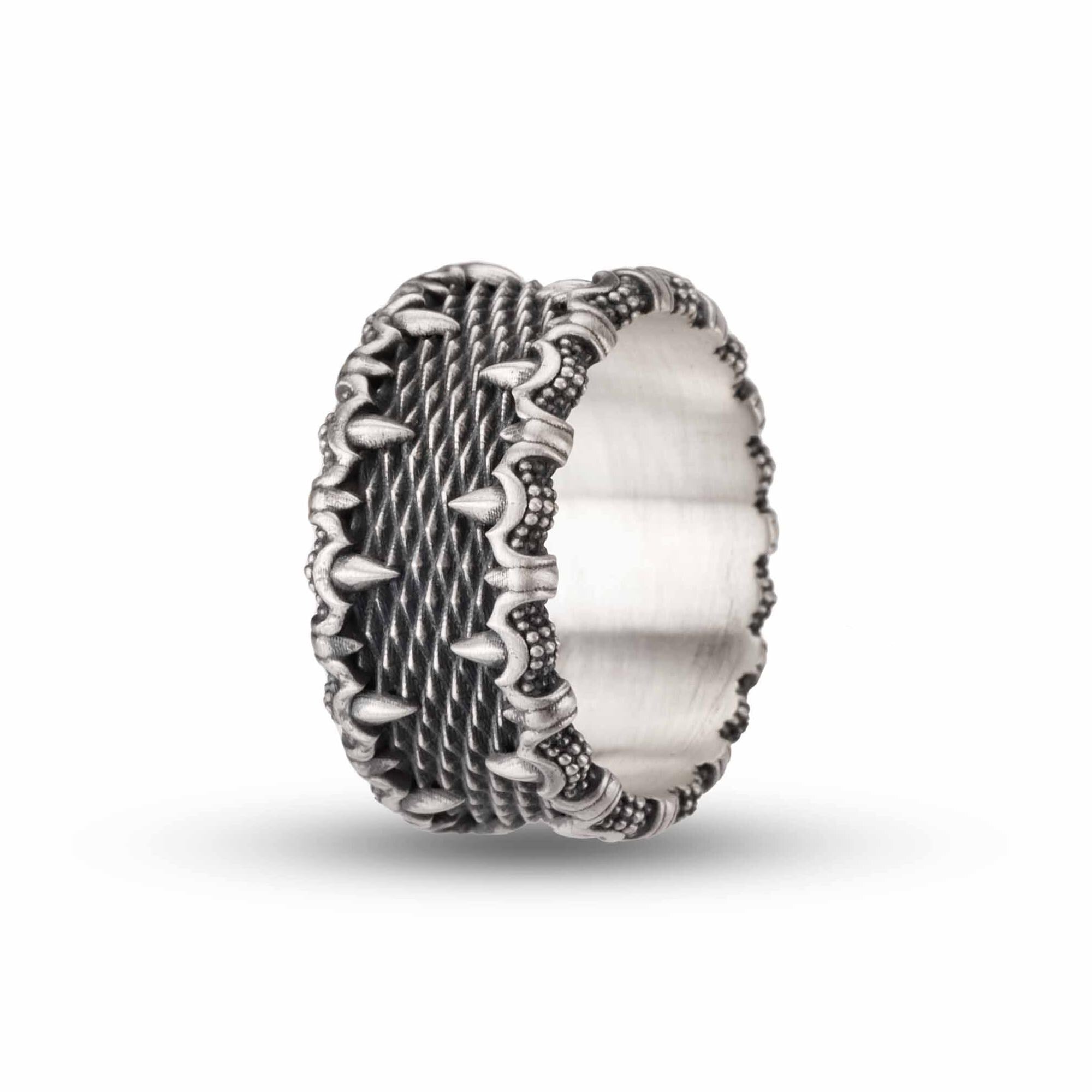 A silver ring with an intricate, textured design featuring spikes or spikes and dots along the edges.