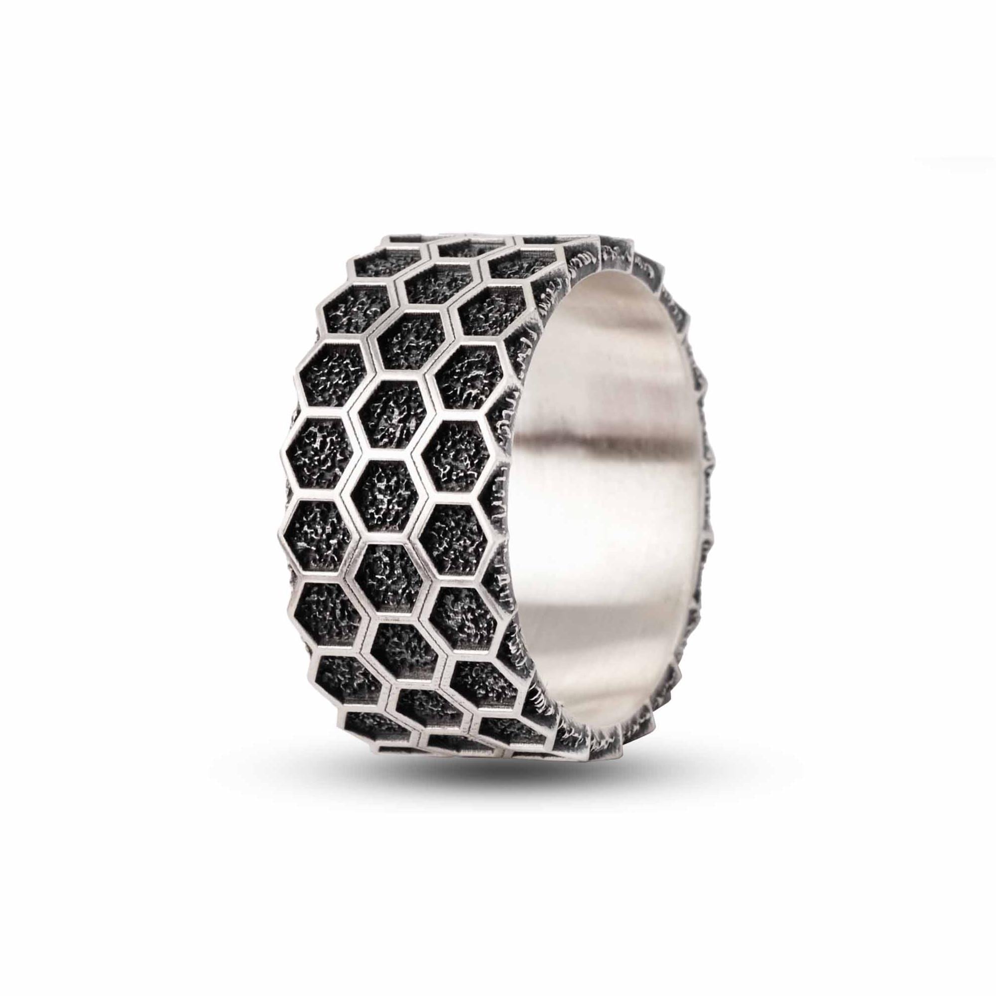 A silver ring with a unique hexagonal pattern, featuring a metallic texture and a metallic sheen.