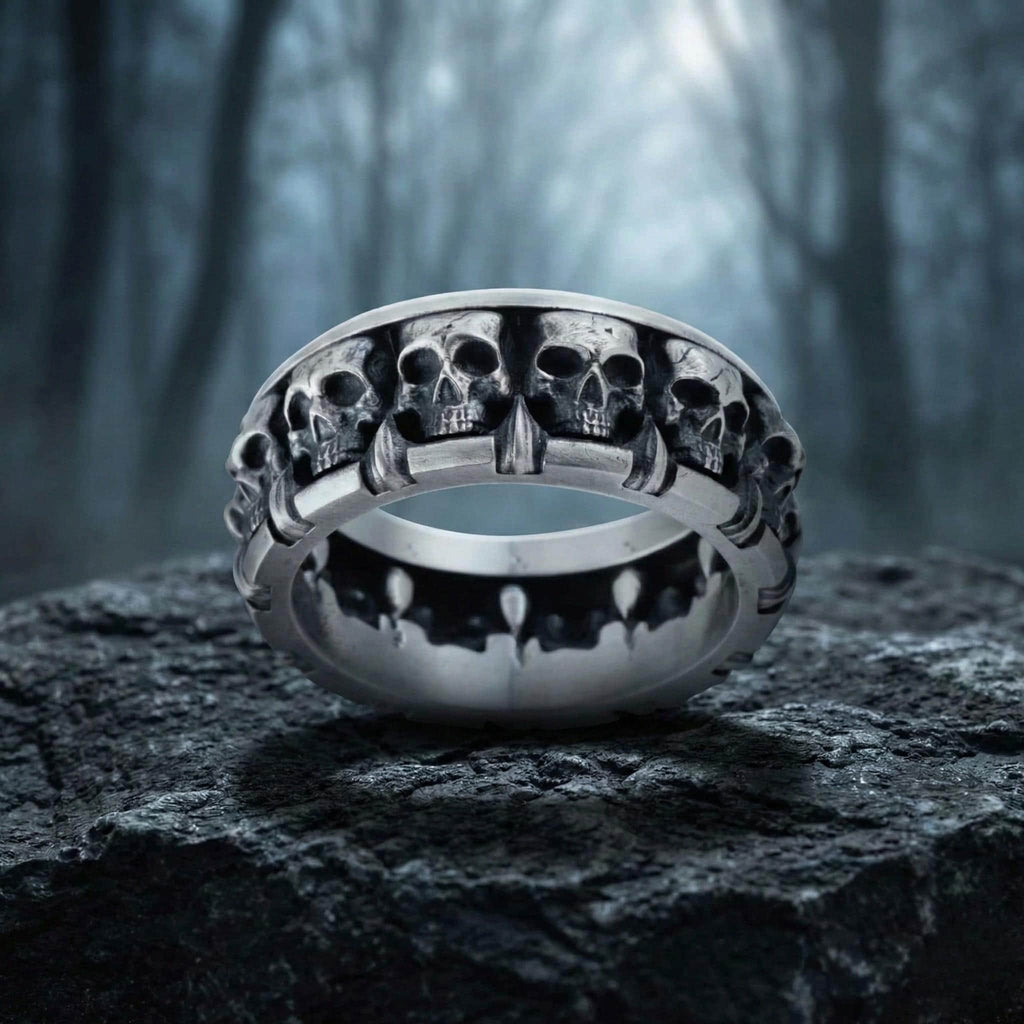 A silver ring with a row of skull designs on it, set against a dark, moody background.