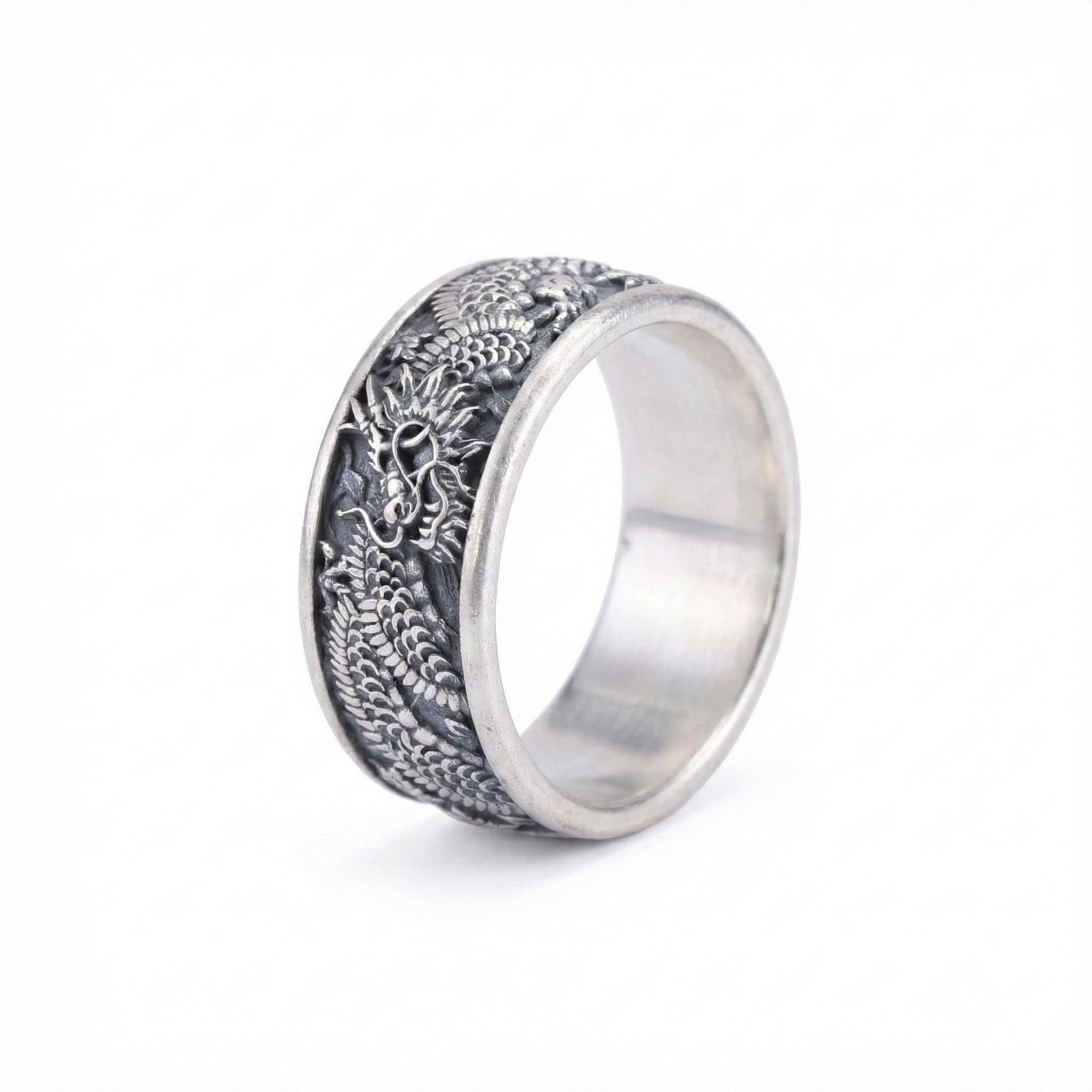 A silver ring with an intricate dragon design on the band.