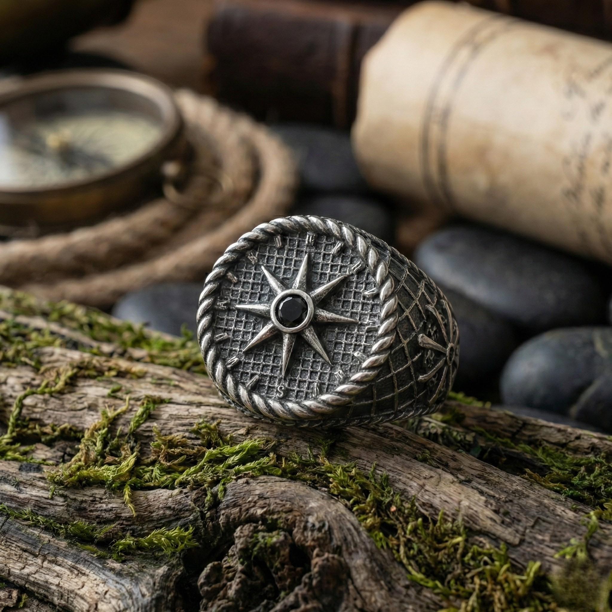 a silver ring with a star design, resting on a mossy log.