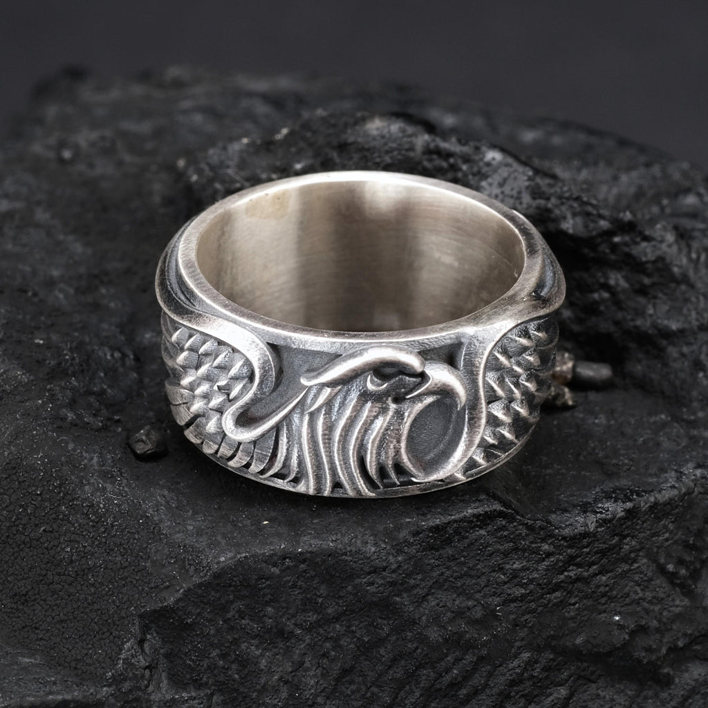 A silver ring with an intricate design featuring a stylized eagle or bird-like figure.