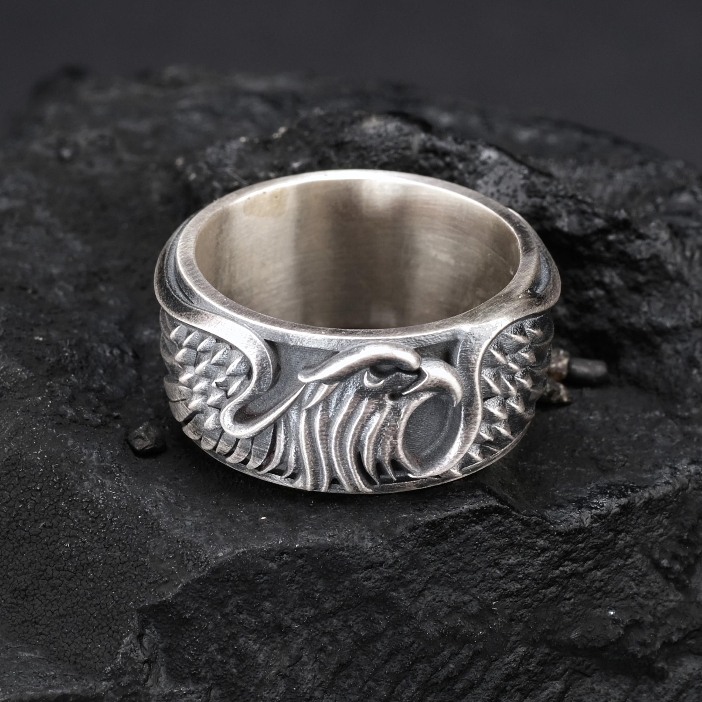 A silver ring with an intricate design featuring a stylized eagle or bird-like figure.