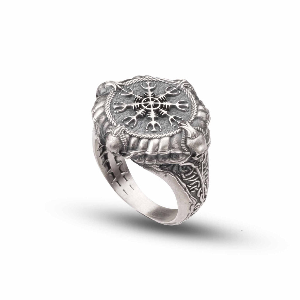 A silver ring with an intricate design featuring a central compass rose surrounded by various symbols and patterns.