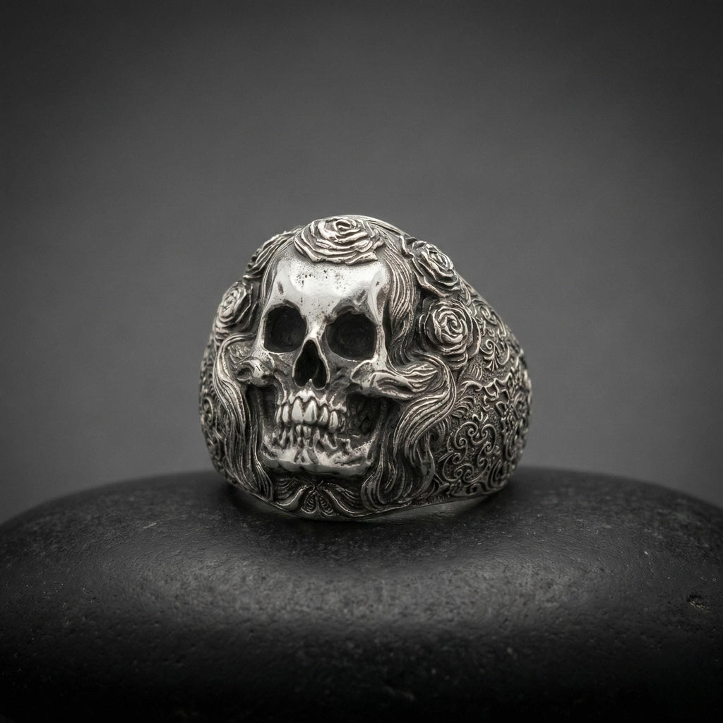A silver skull ring with intricate floral designs on the surface.