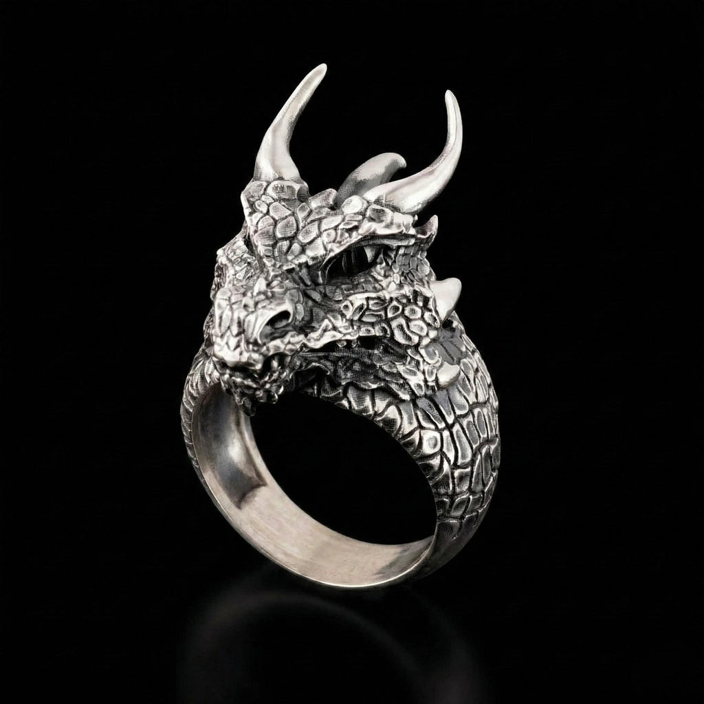 A silver ring in the shape of a fierce dragon's head with sharp horns and a textured body.