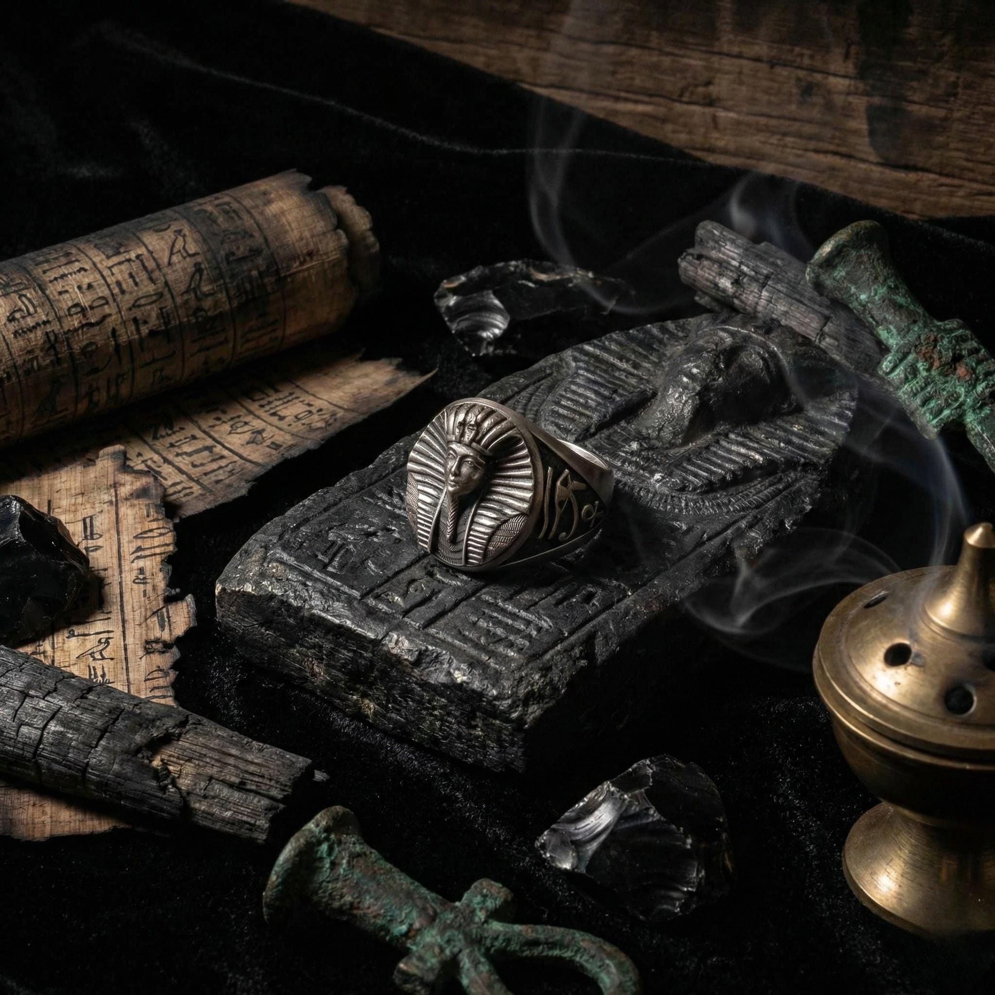 a collection of ancient artifacts and symbols, including a ring with a pharaoh's head, a scroll, and a casket, all set against a dark background.