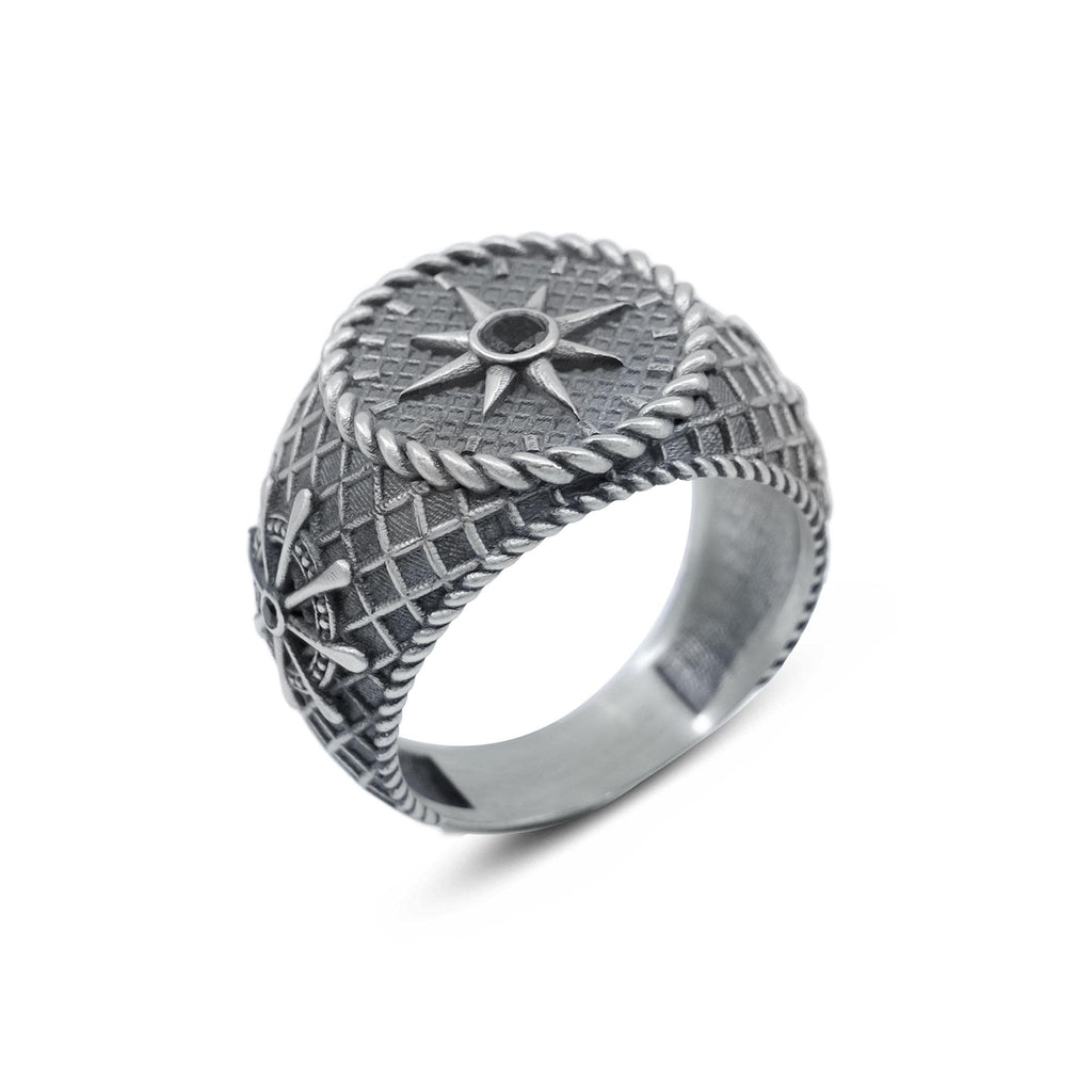 A silver ring with intricate designs and patterns, including a star motif and a rope-like element.
