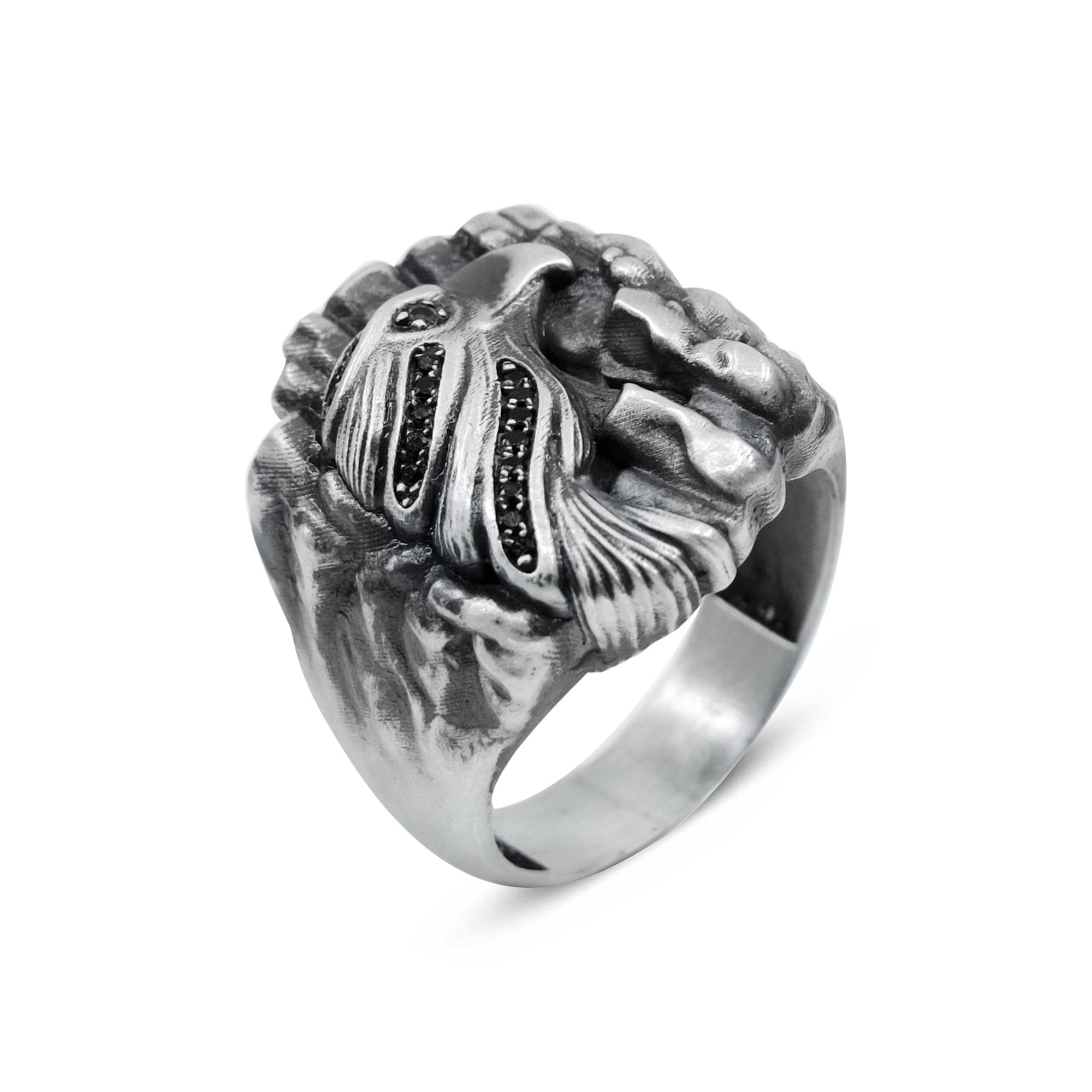 A silver ring with a detailed design featuring a bird-like figure and small black stones.