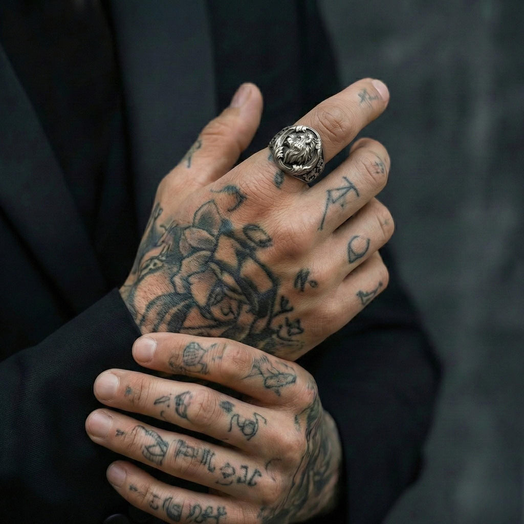 a close-up of a person's hands with tattoos on them, wearing a ring on one of the fingers.