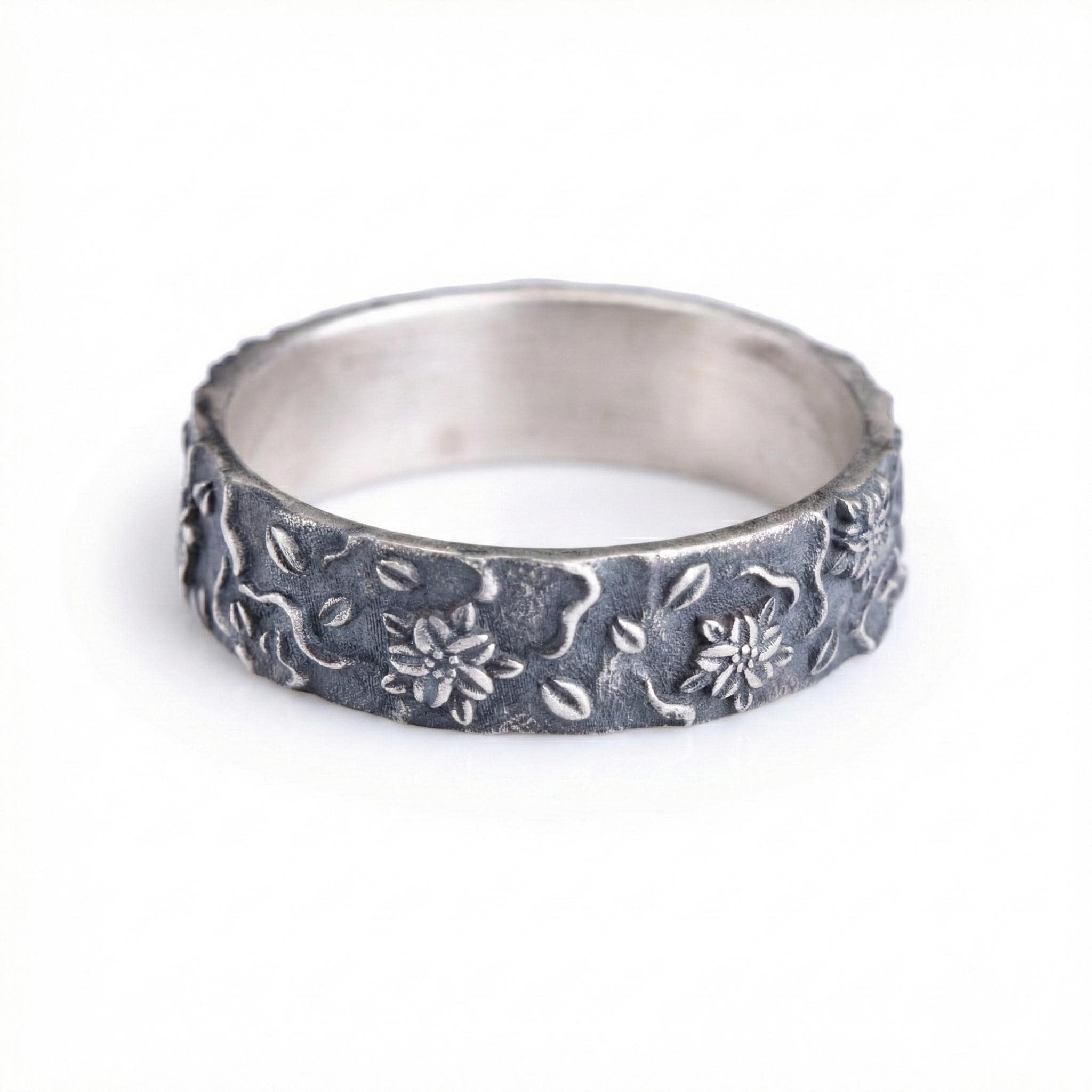 A silver ring with a floral design on the band.