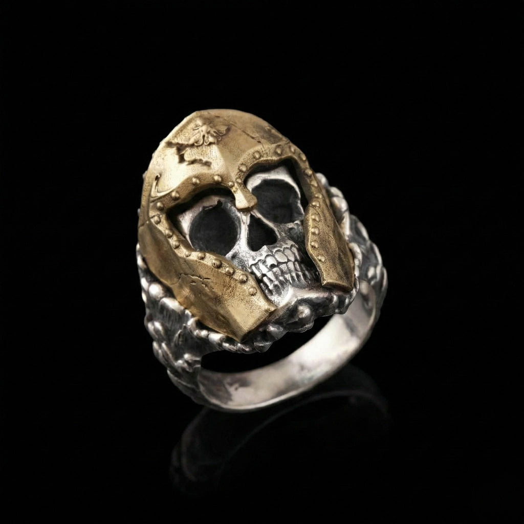 A ring featuring a skull design with a golden helmet, set against a black background.