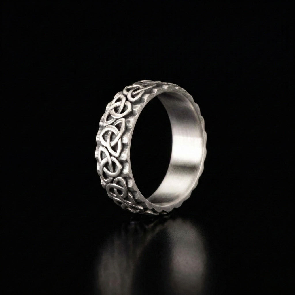 A silver ring with an intricate, decorative design on a black background.