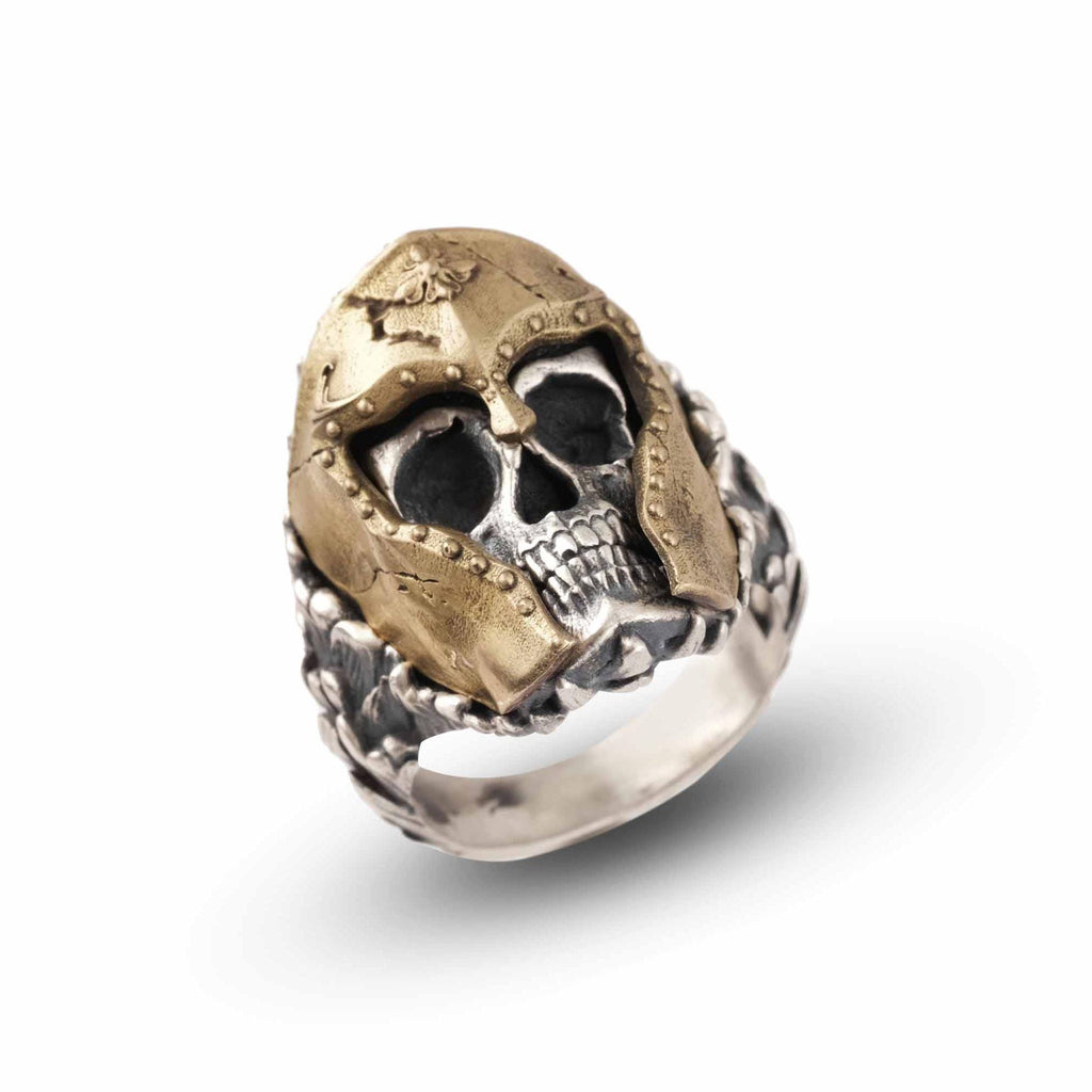 A ring featuring a detailed, intricately designed skull with a golden-colored metal helmet or headpiece.