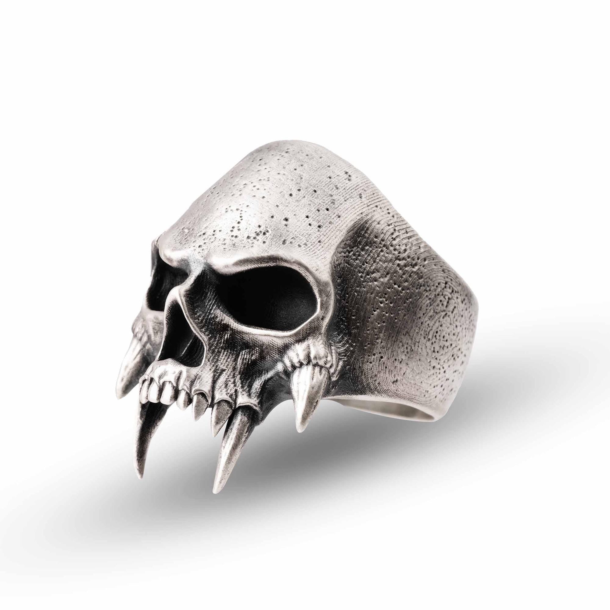 A silver ring in the shape of a skull with sharp teeth protruding from the sides.