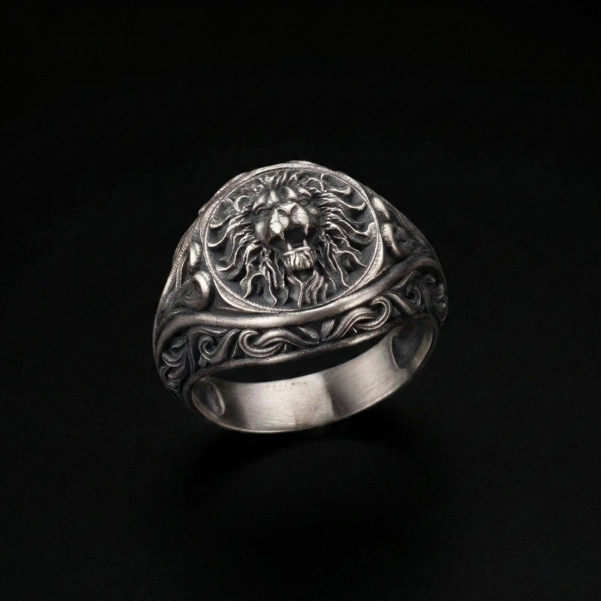 A silver ring with an intricate design featuring a lion's head or a similar animal head.