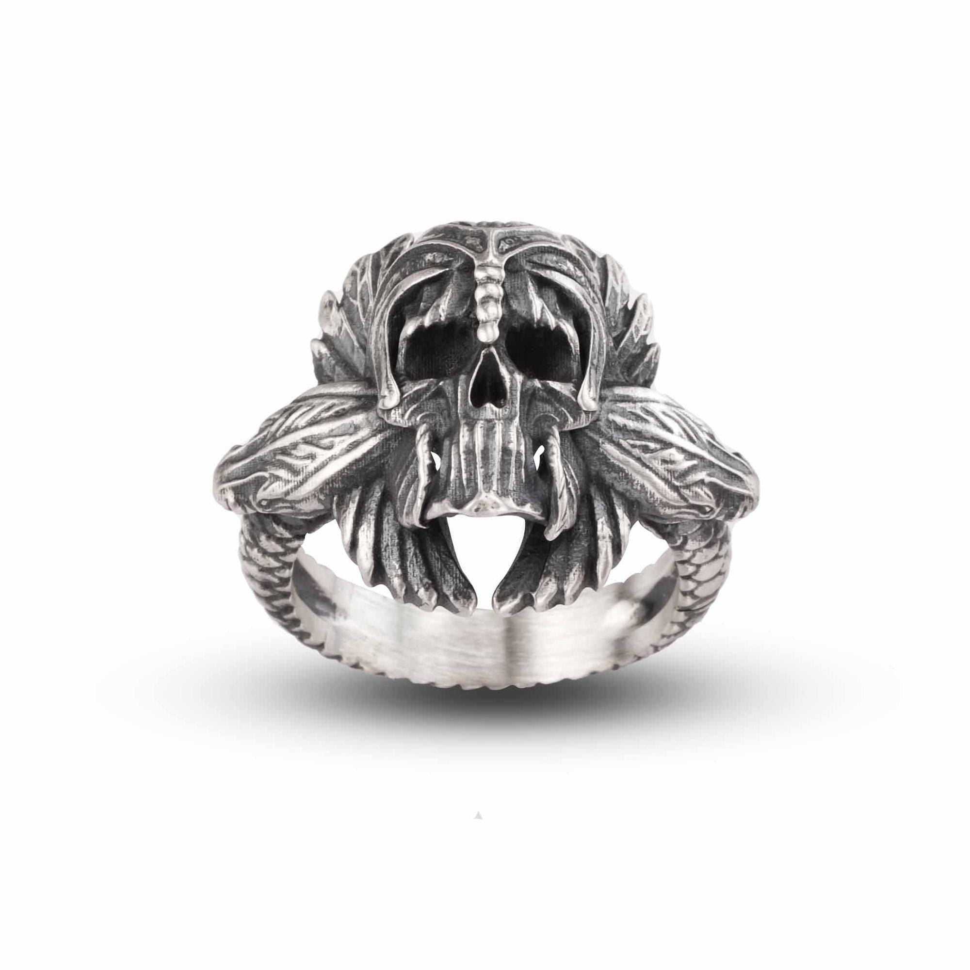 A silver ring with an intricate design featuring a skull and two snakes.