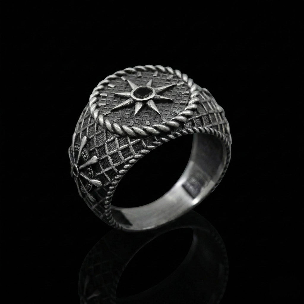 A silver ring with intricate designs and a central star-shaped motif, set against a black background.