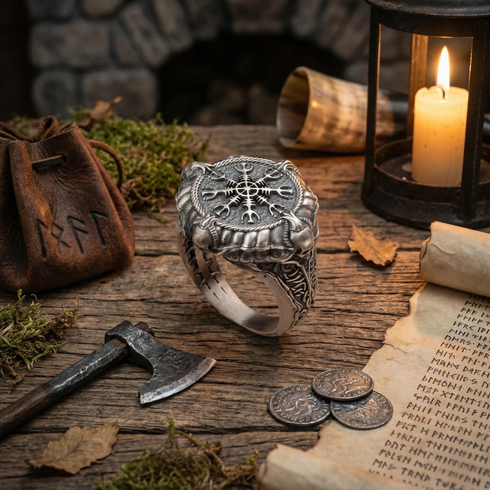 a ring with a compass design, a lantern, a scroll, a coin, a knife, and a bag with the letters "RÆF" on it, all arranged on a wooden surface.
