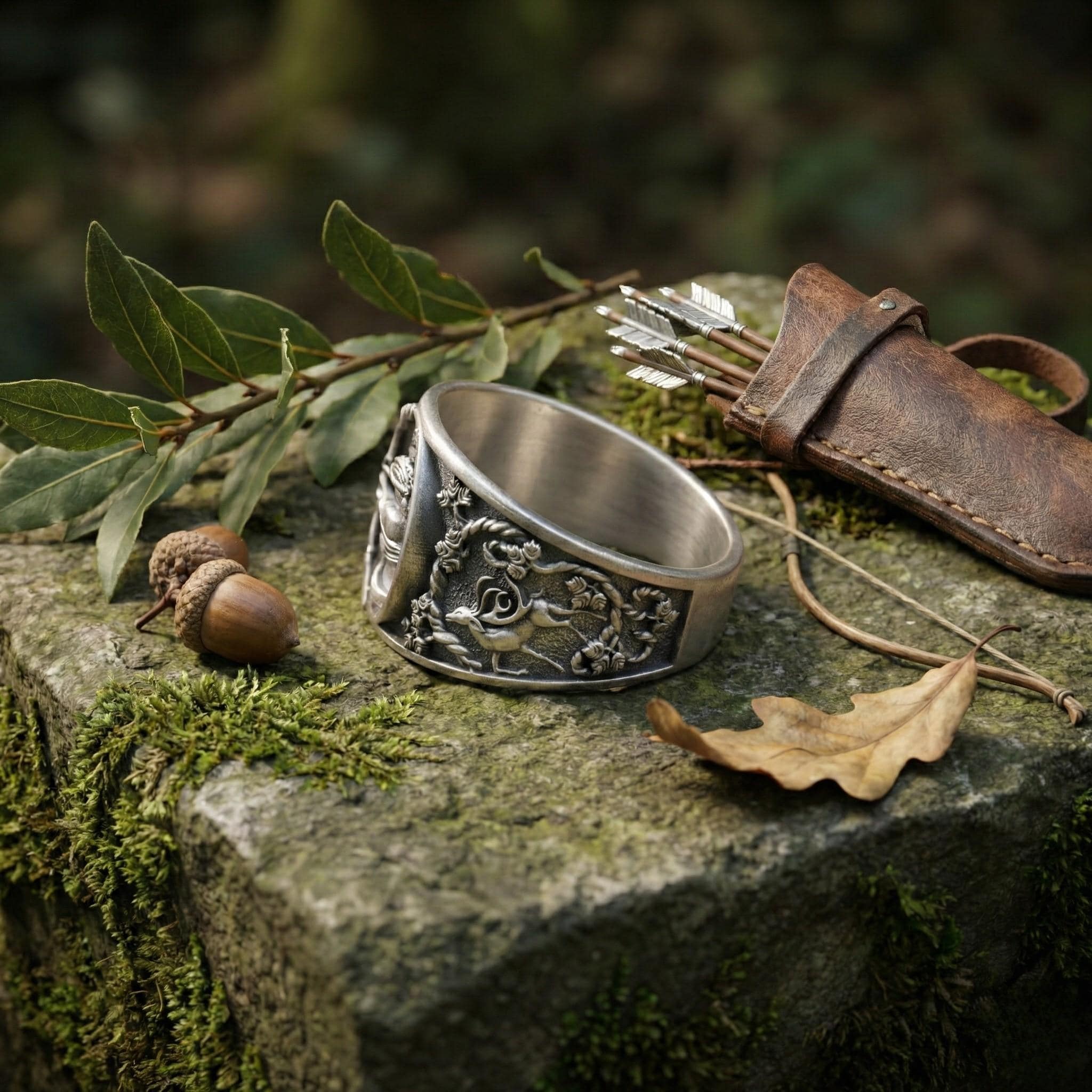 A silver ring with a decorative design sits on a mossy rock, surrounded by leaves, acorns, and a leather pouch containing arrows.