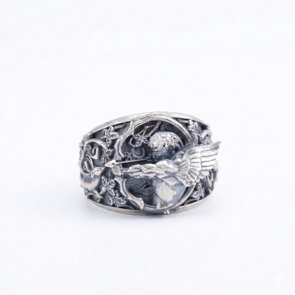 A silver ring with an intricate design featuring a cherubic figure and wings.