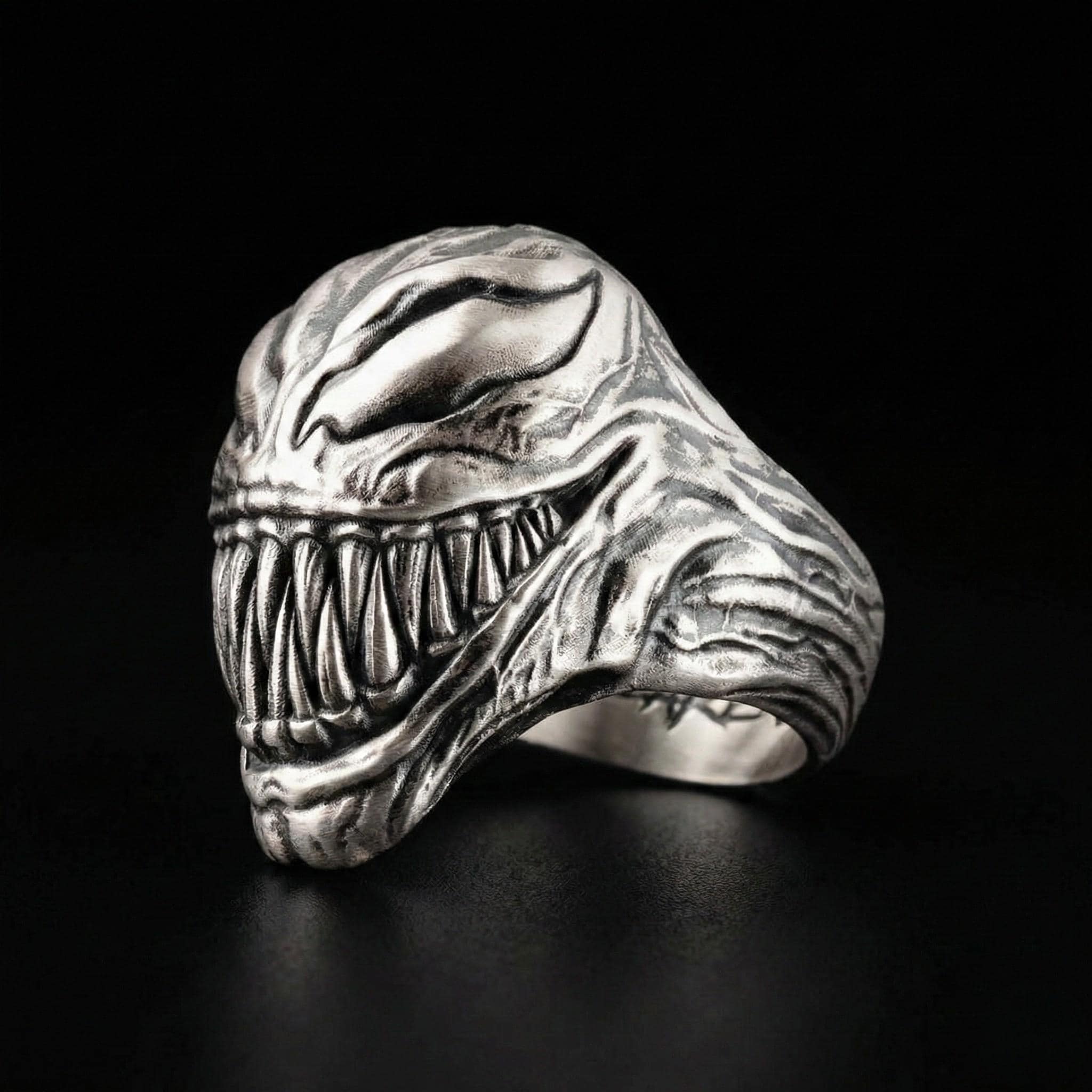A silver ring with a detailed, menacing-looking creature design, resembling a monster or a dangerous animal.