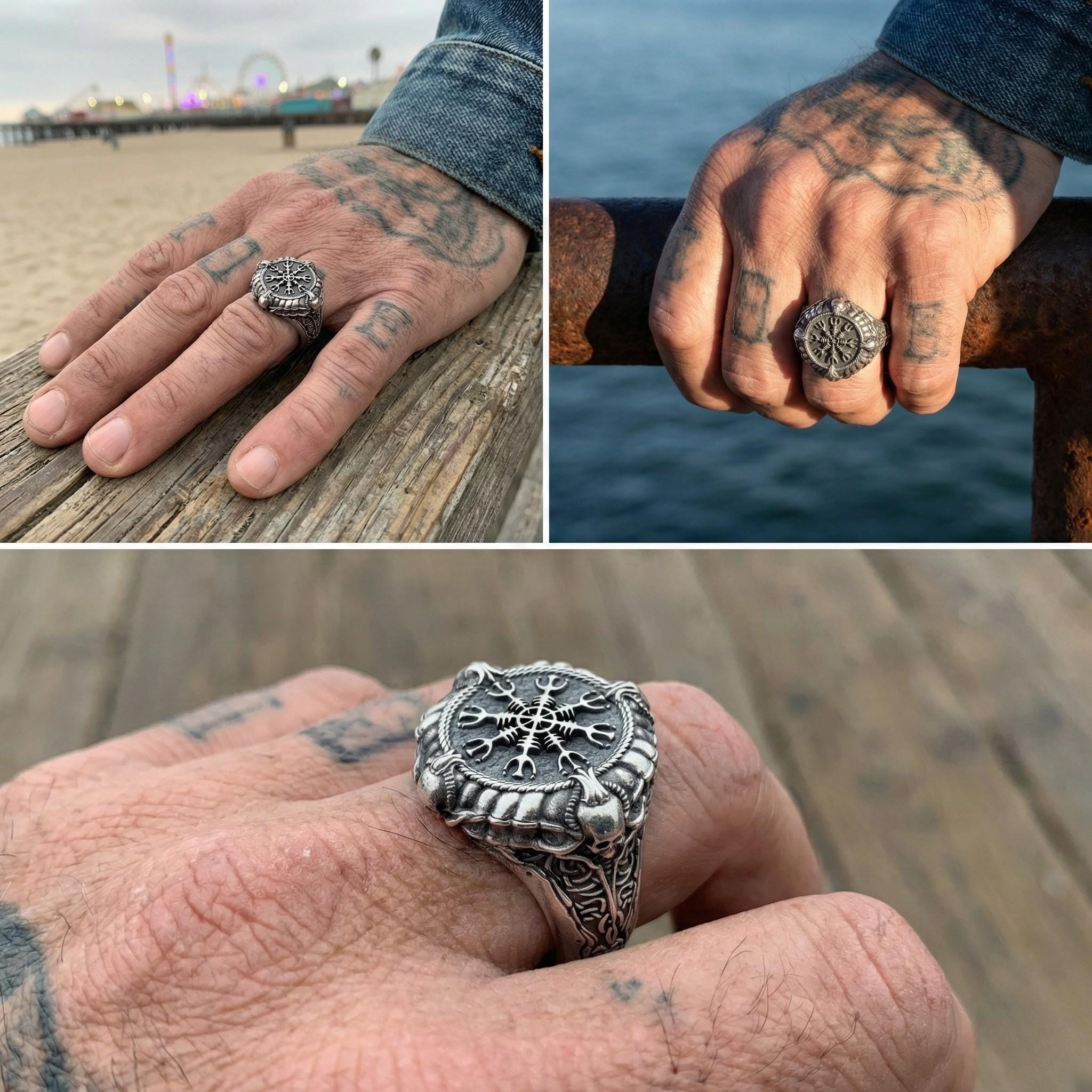 A close-up of a person's hand wearing a large, ornate ring with a compass design. The hand is positioned on a wooden surface, with a pier and a body of water visible in the background.