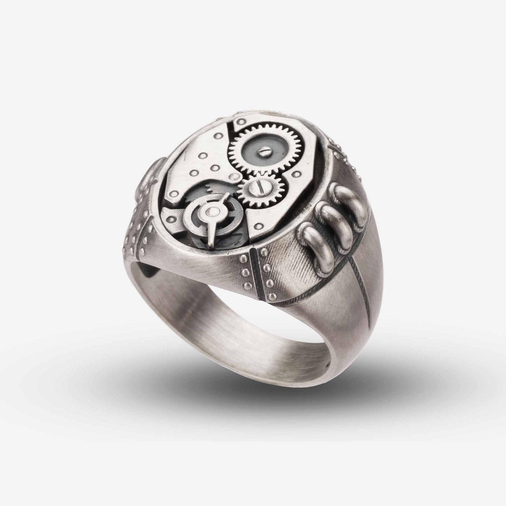 A silver ring with a mechanical design, featuring gears and other intricate details.
