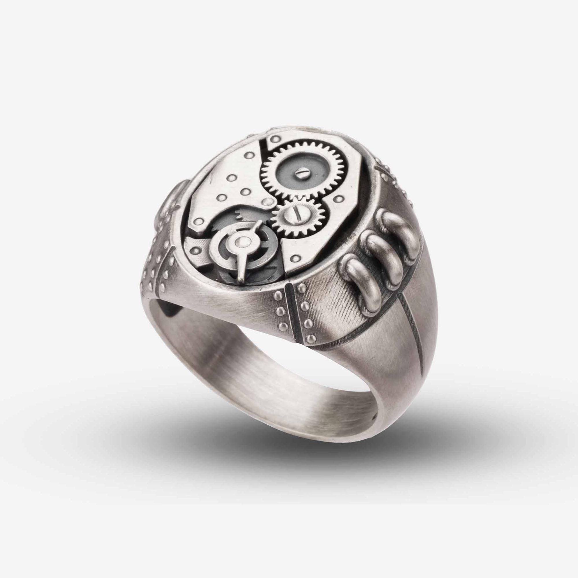 A silver ring with a mechanical design, featuring gears and other intricate details.