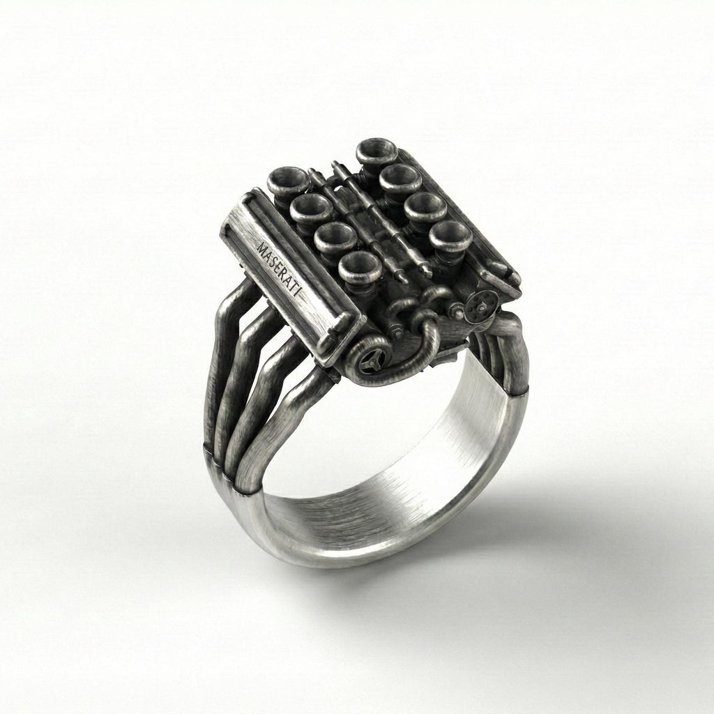 A silver ring with an intricate design resembling an engine or a mechanical device.