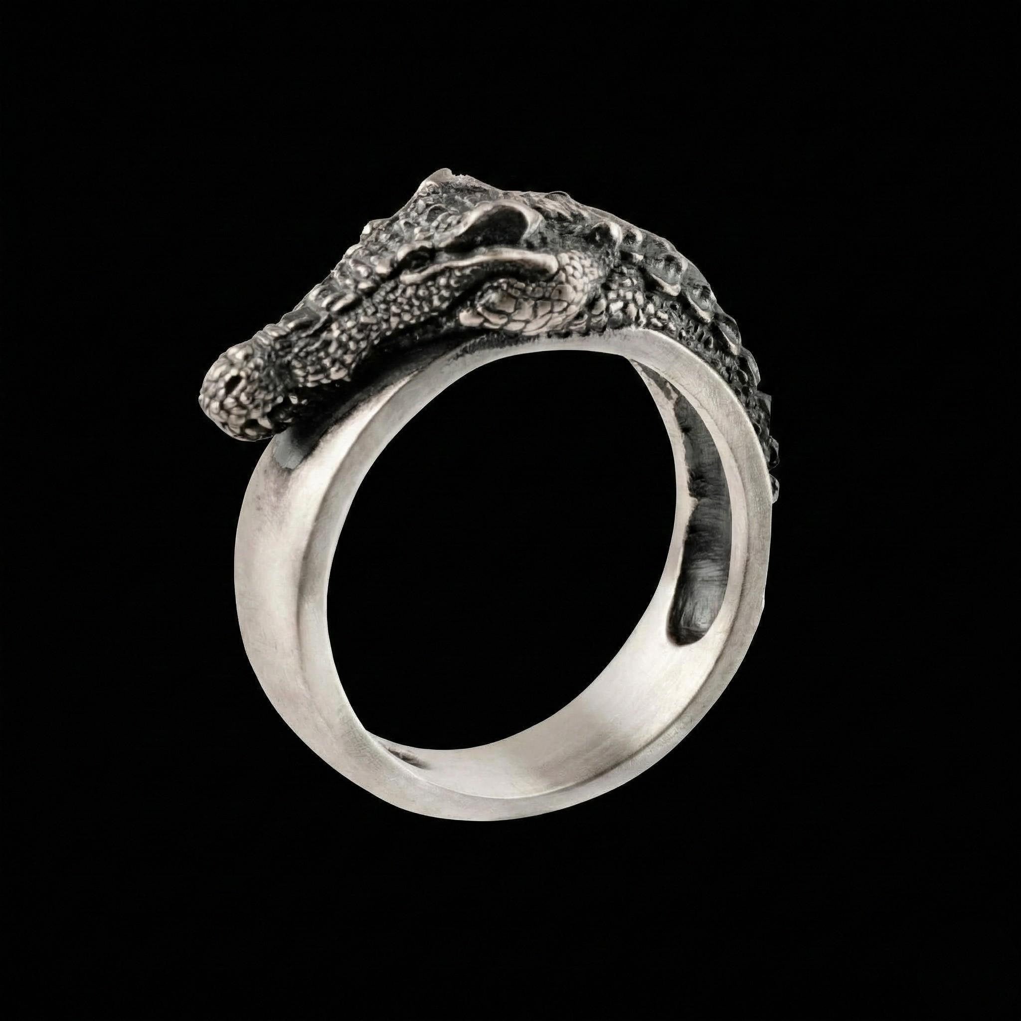A silver ring with a crocodile head design on it.
