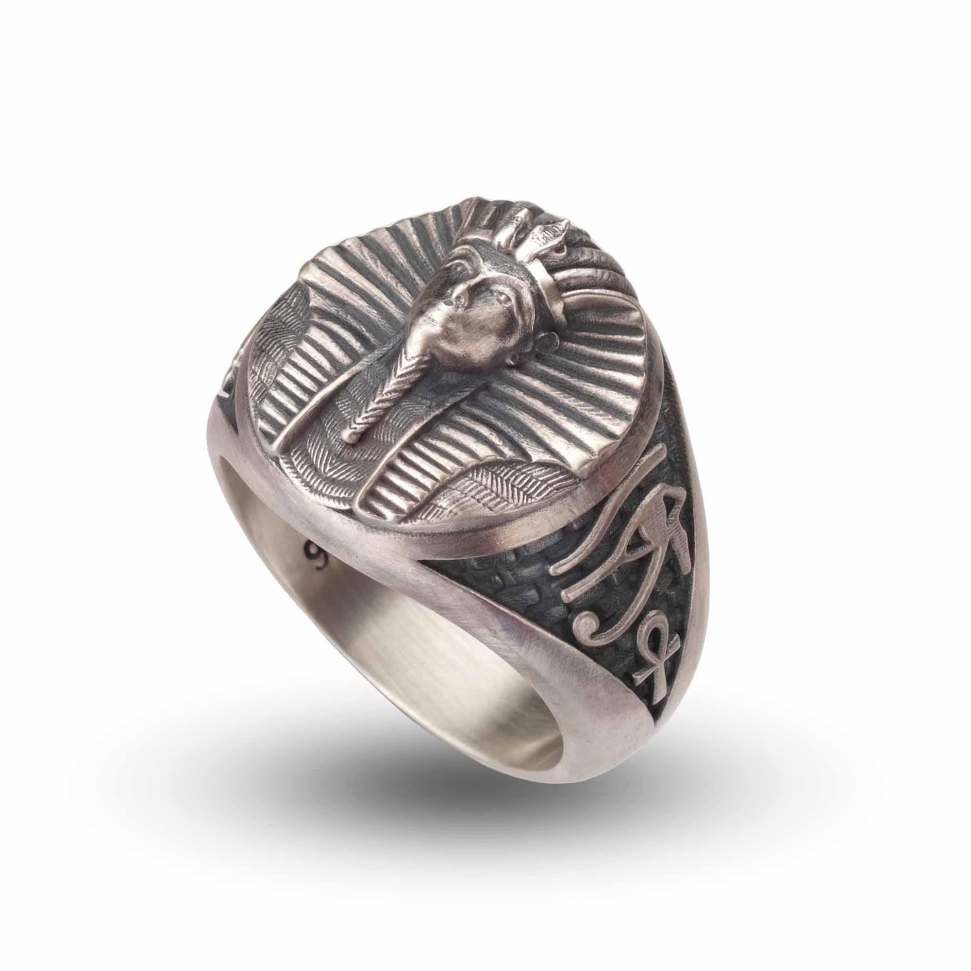 a silver ring with an embossed design of a pharaoh's head.