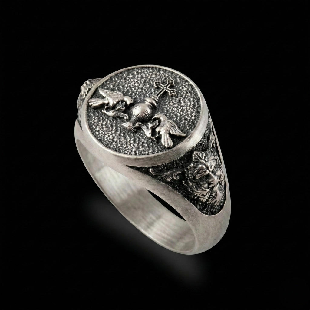 A silver ring with an intricate design featuring a cross, a lion, and a bird.