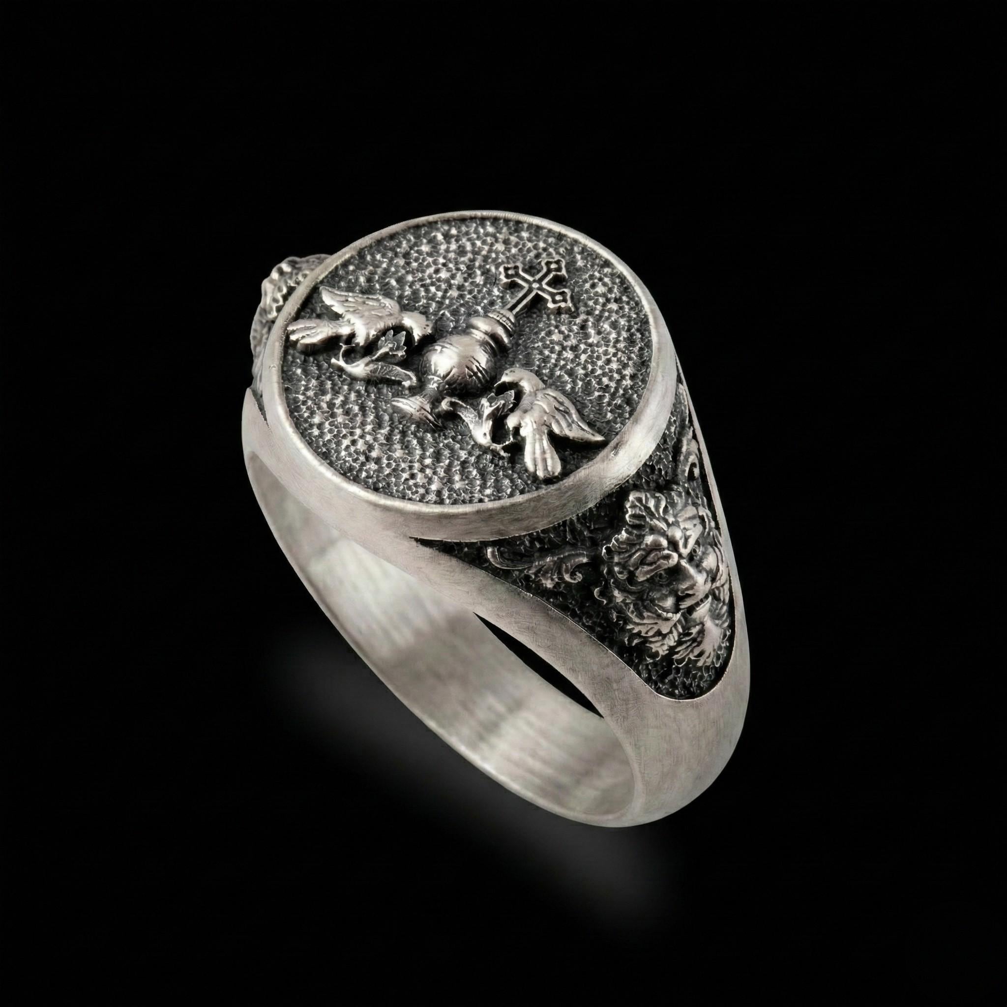 A silver ring with an intricate design featuring a cross, a lion, and a bird.
